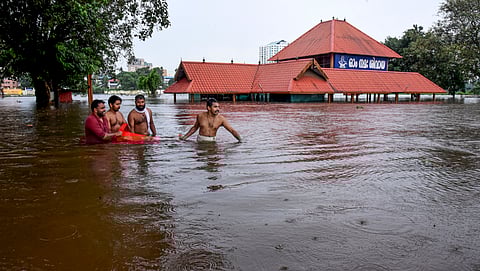 People make their way through a flooded area near the Aluva Mahadeva Temple which got partially submerged due to rising water levels of the Periyar river following heavy rains, in Kochi district, Tuesday, July 16